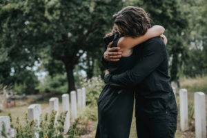 husband trying to comfort his wife at graveyard