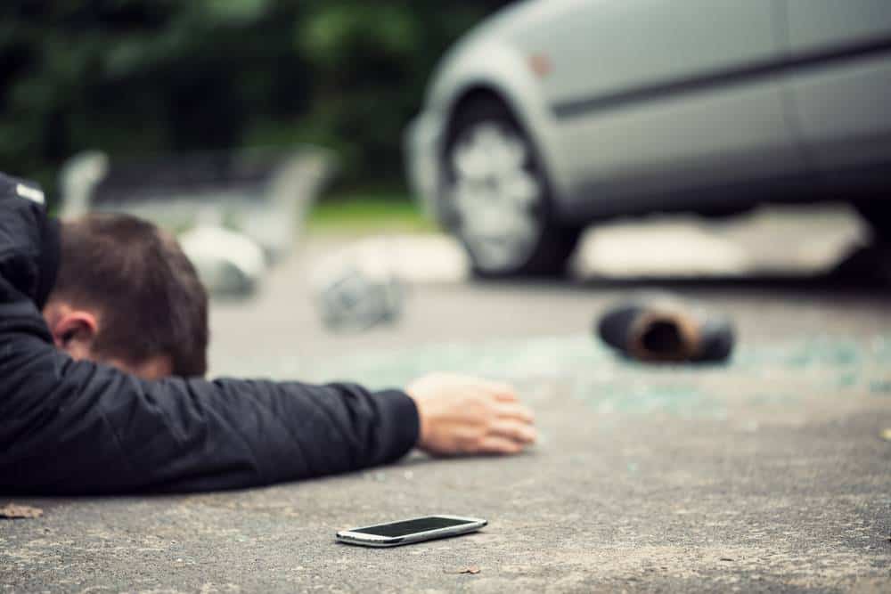 victim on ground with scattered items and car in background