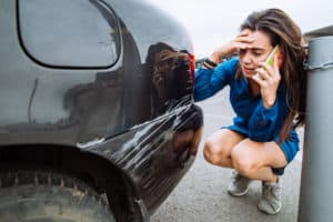 woman making a call near a scratched vehicle